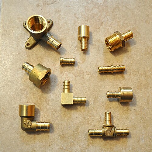 Brass elbows, couplings and threaded plumbing fittings laid out on a surface