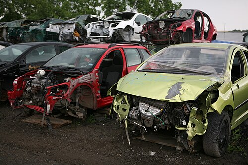Dismantled car bodies in a scrap yard with doors and engine parts removed