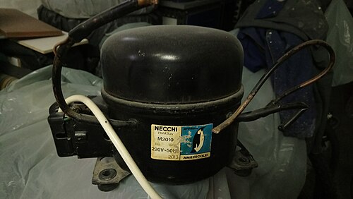 A used black fridge compressor with attached pipe connections