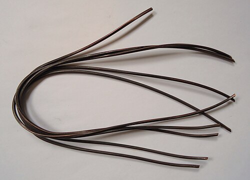 Lengths of darkened bare copper wire laid out on a light surface