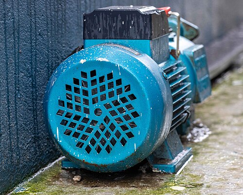 A weathered electric water pump with blue motor housing and ventilation grille