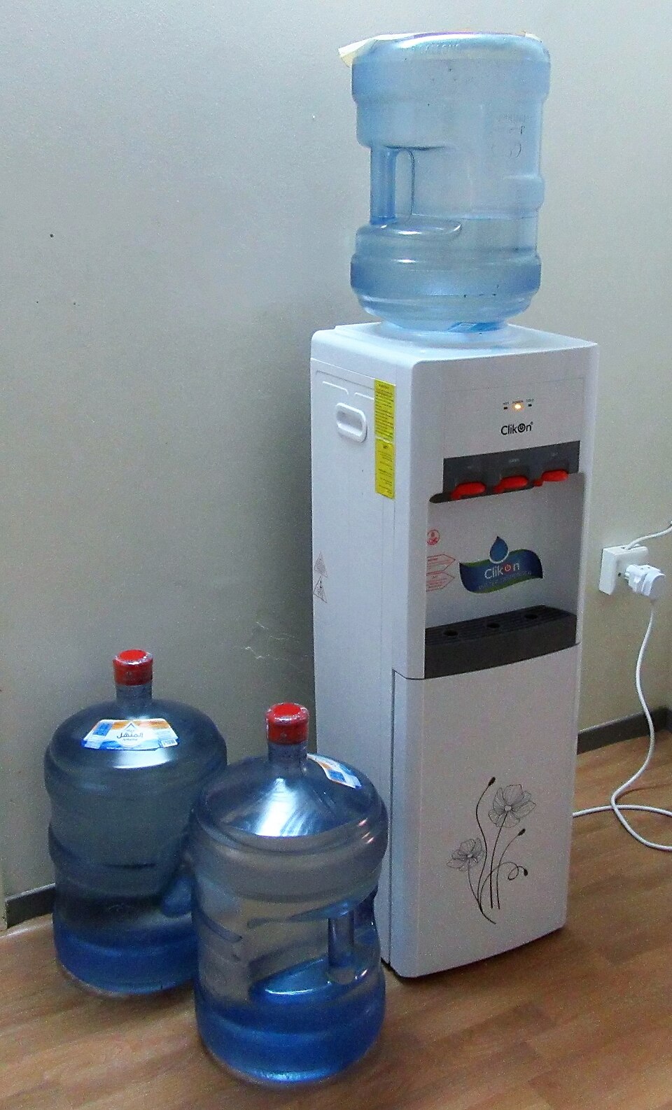 A freestanding water dispenser with a blue bottle and three taps